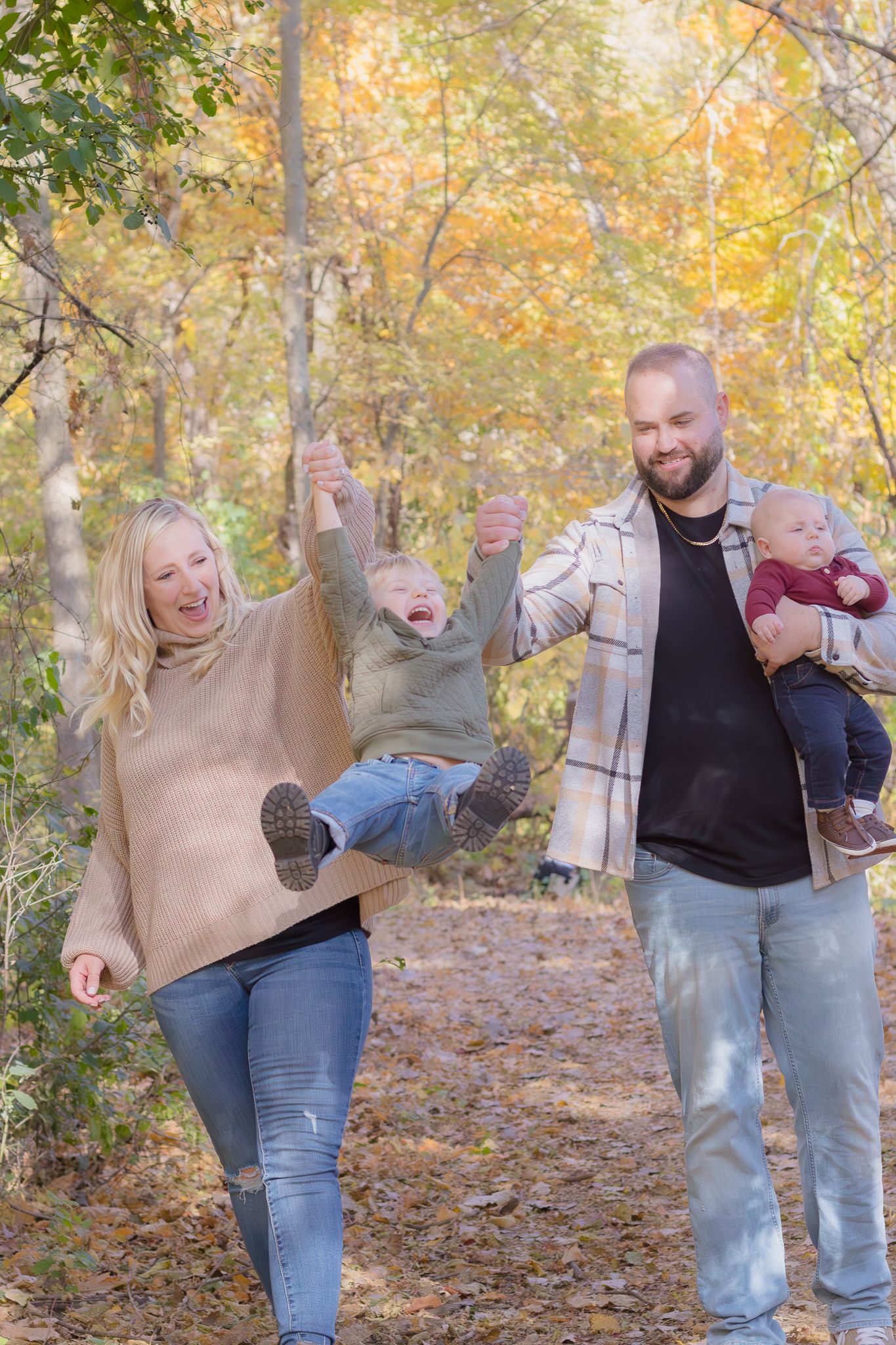 A playful family moment on an autumn trail with falling leaves.