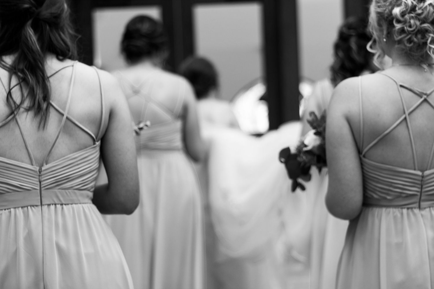 Black and white photo showing a row of bridesmaids holding elegant bouquets at a formal wedding.