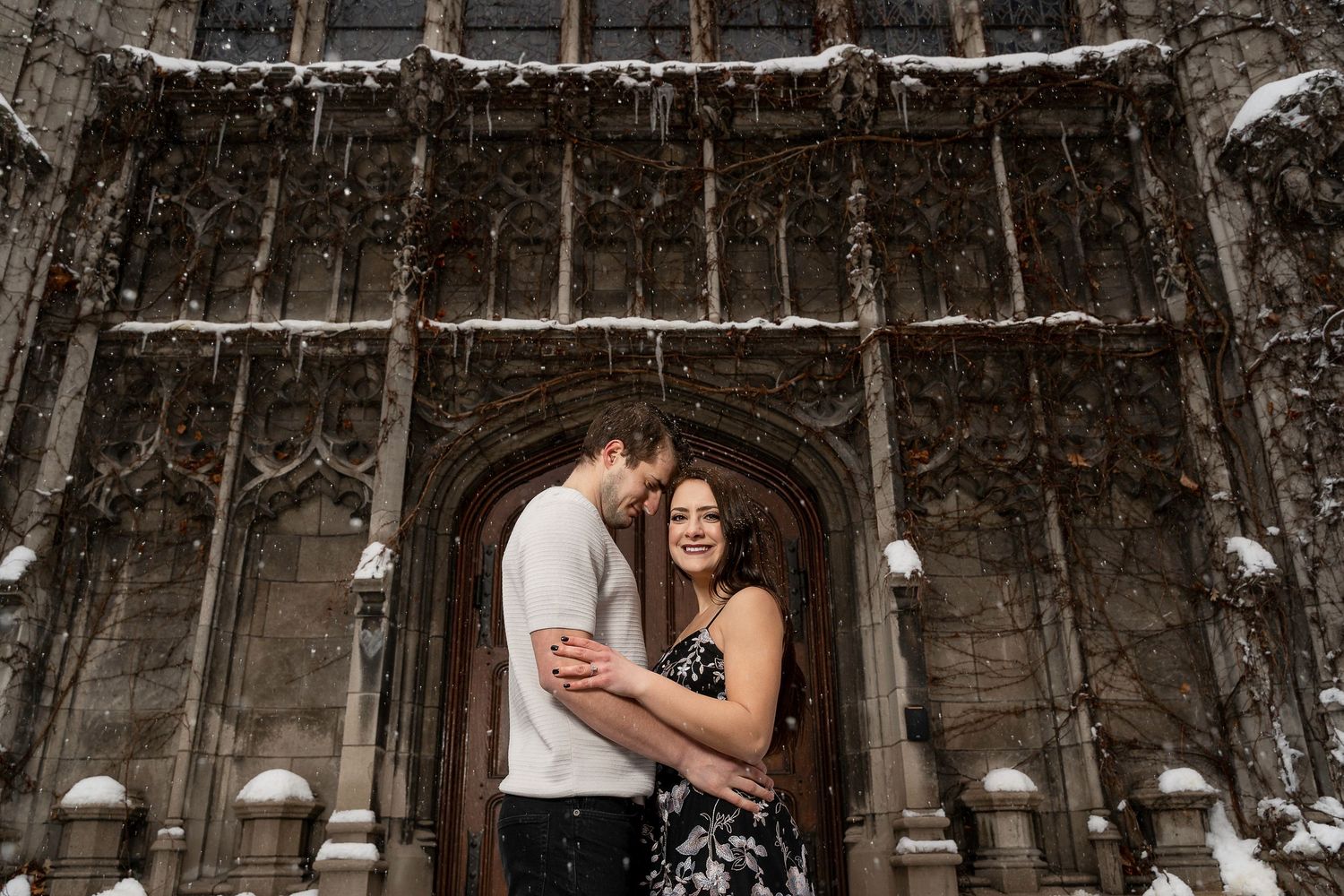 Couple embracing in romantic pose under gothic archway with hanging lights.