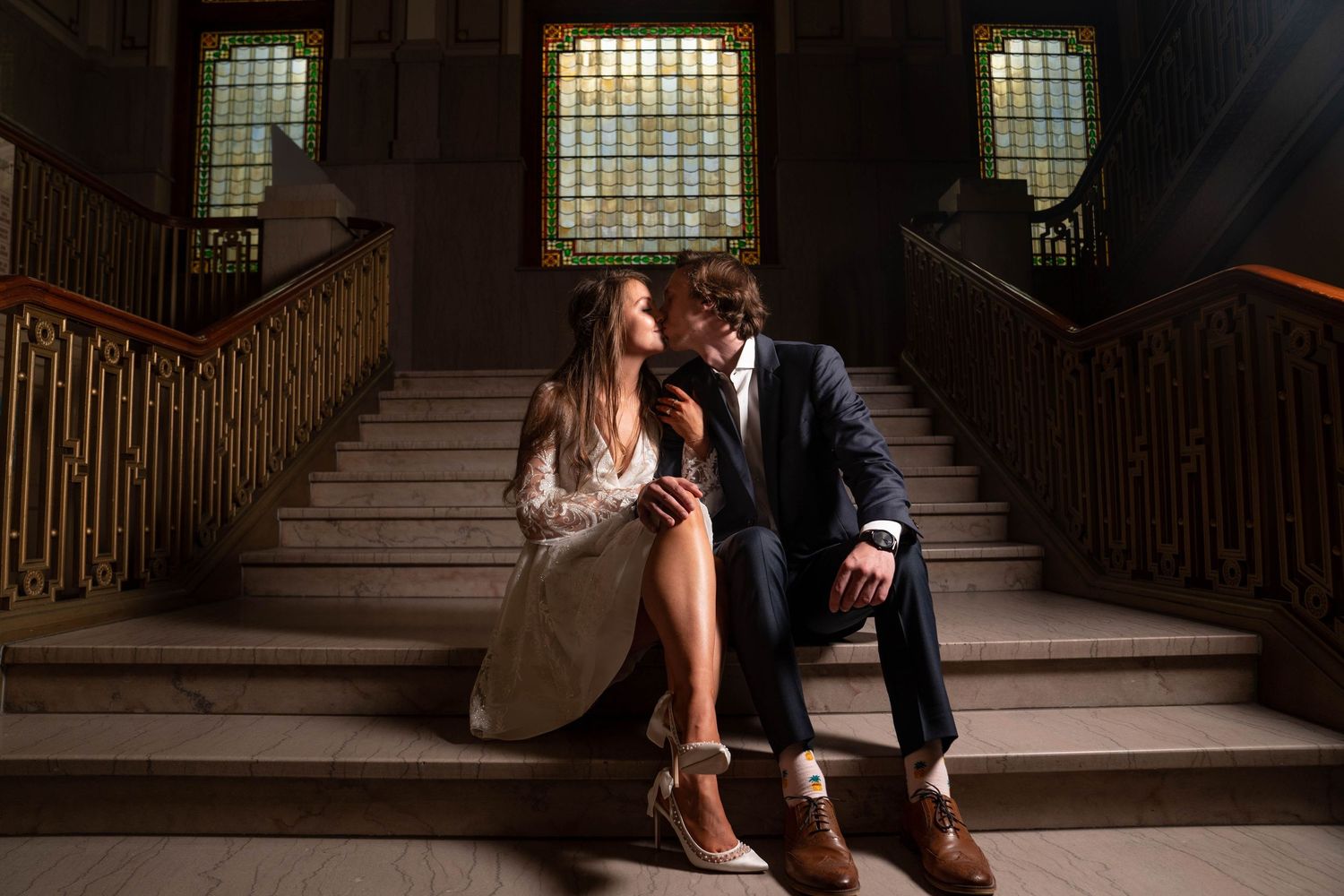 Couple sitting intimately on grand staircase in historic building.