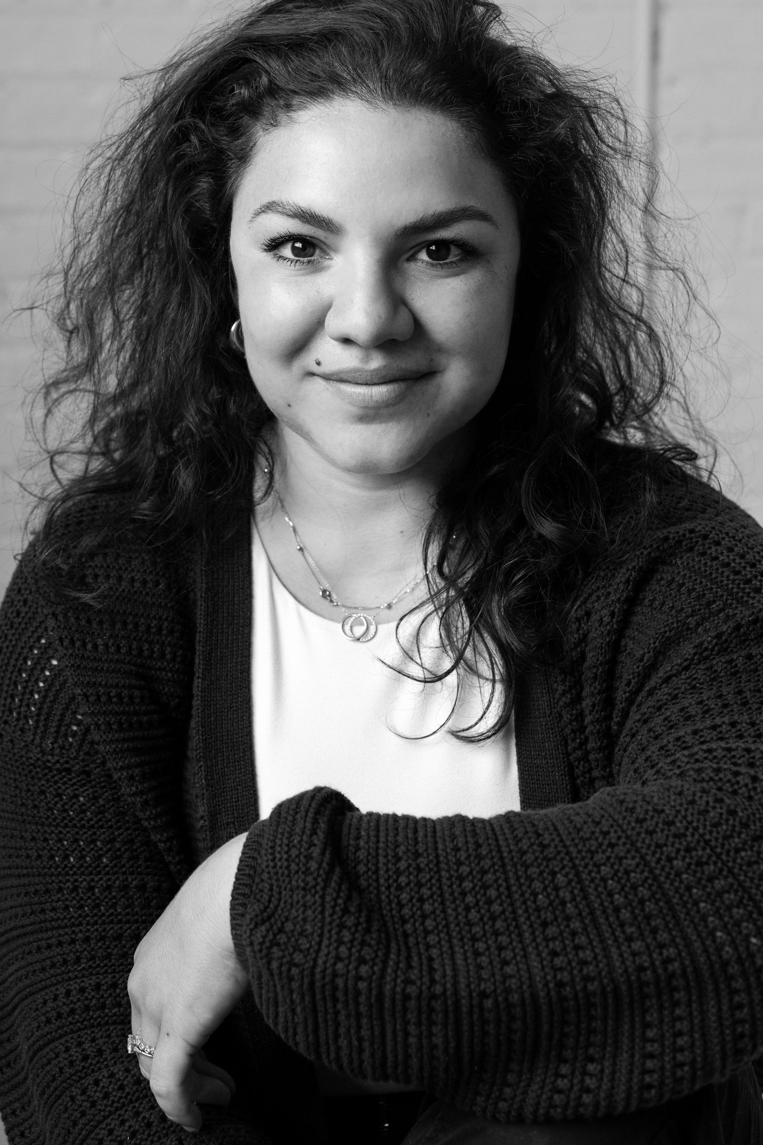 Black and white portrait of person in cozy knit cardigan.