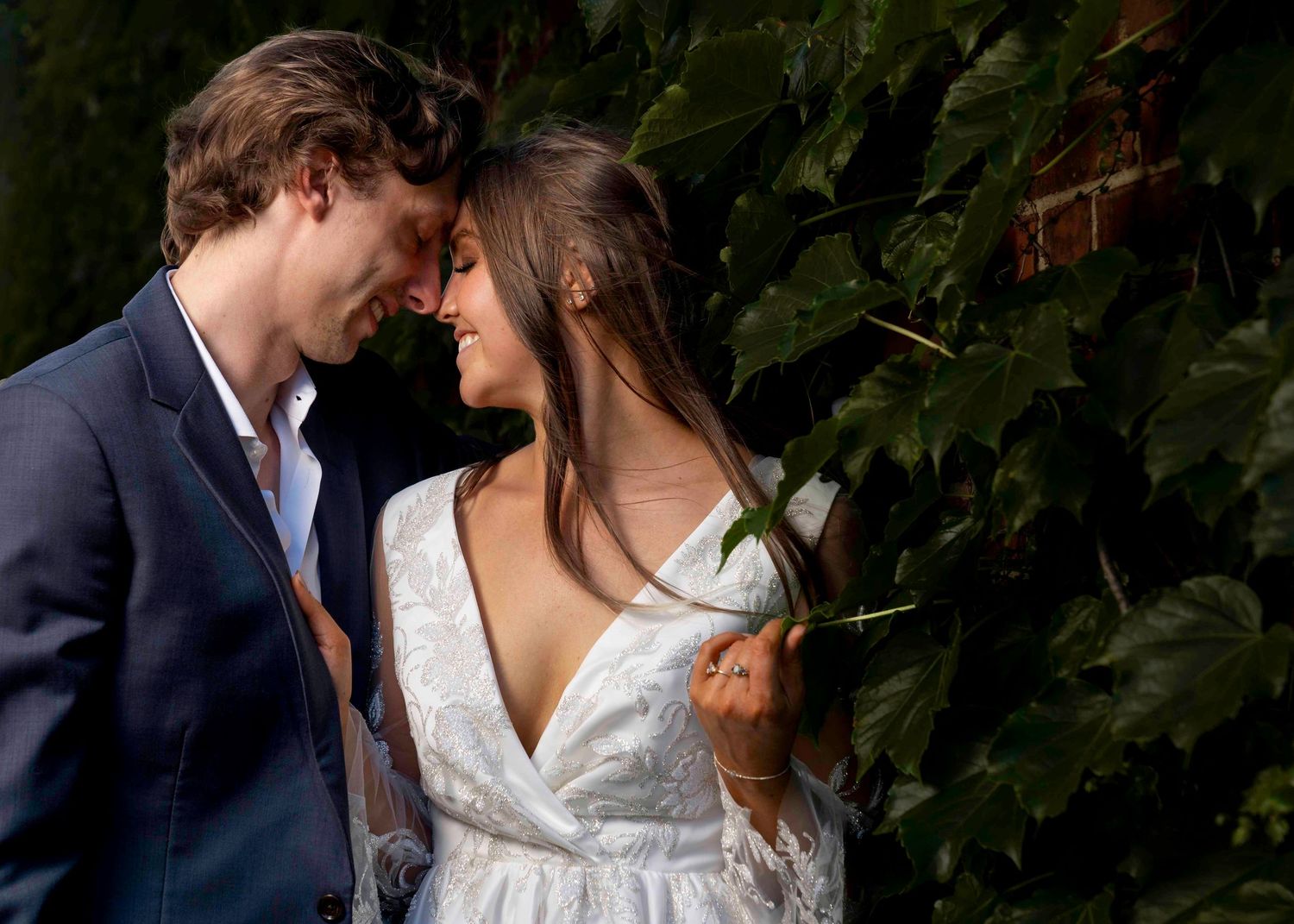 Romantic moment between couple against lush green foliage backdrop.