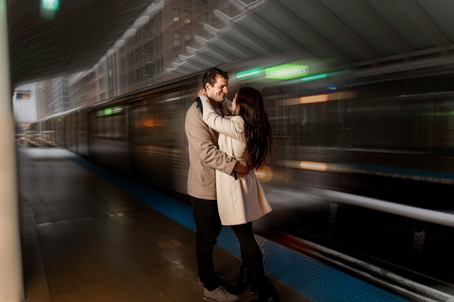Couple sharing intimate moment in subway station with motion blur in background.