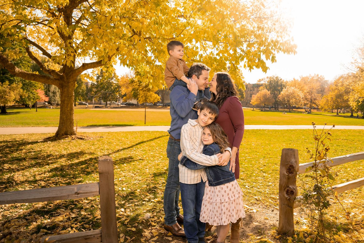 Loving couple shares intimate moments in a park with golden autumn foliage during sunset photo session.