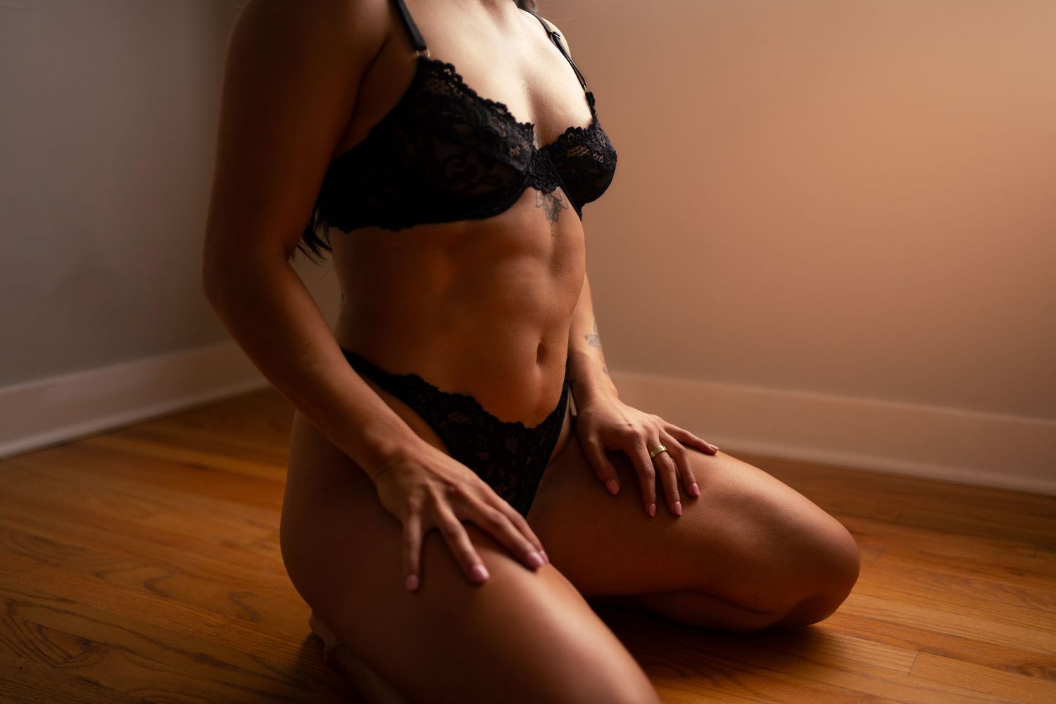 Intimate boudoir photography with warm lighting on wooden floor.