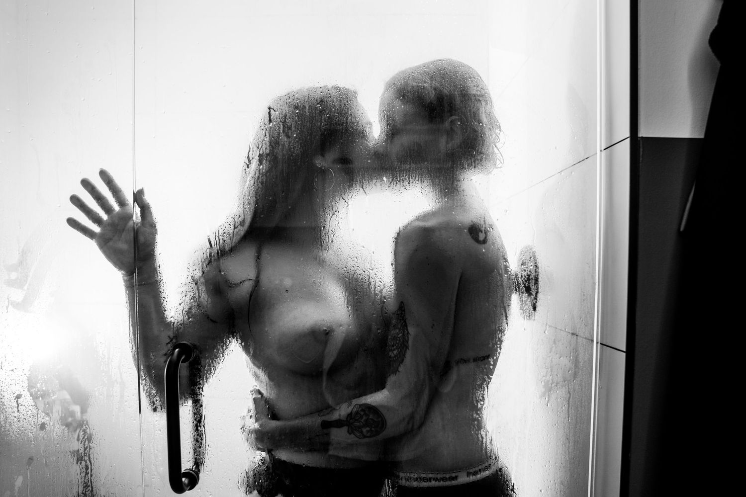 Silhouette of two people through steamy glass creating an intimate artistic composition.