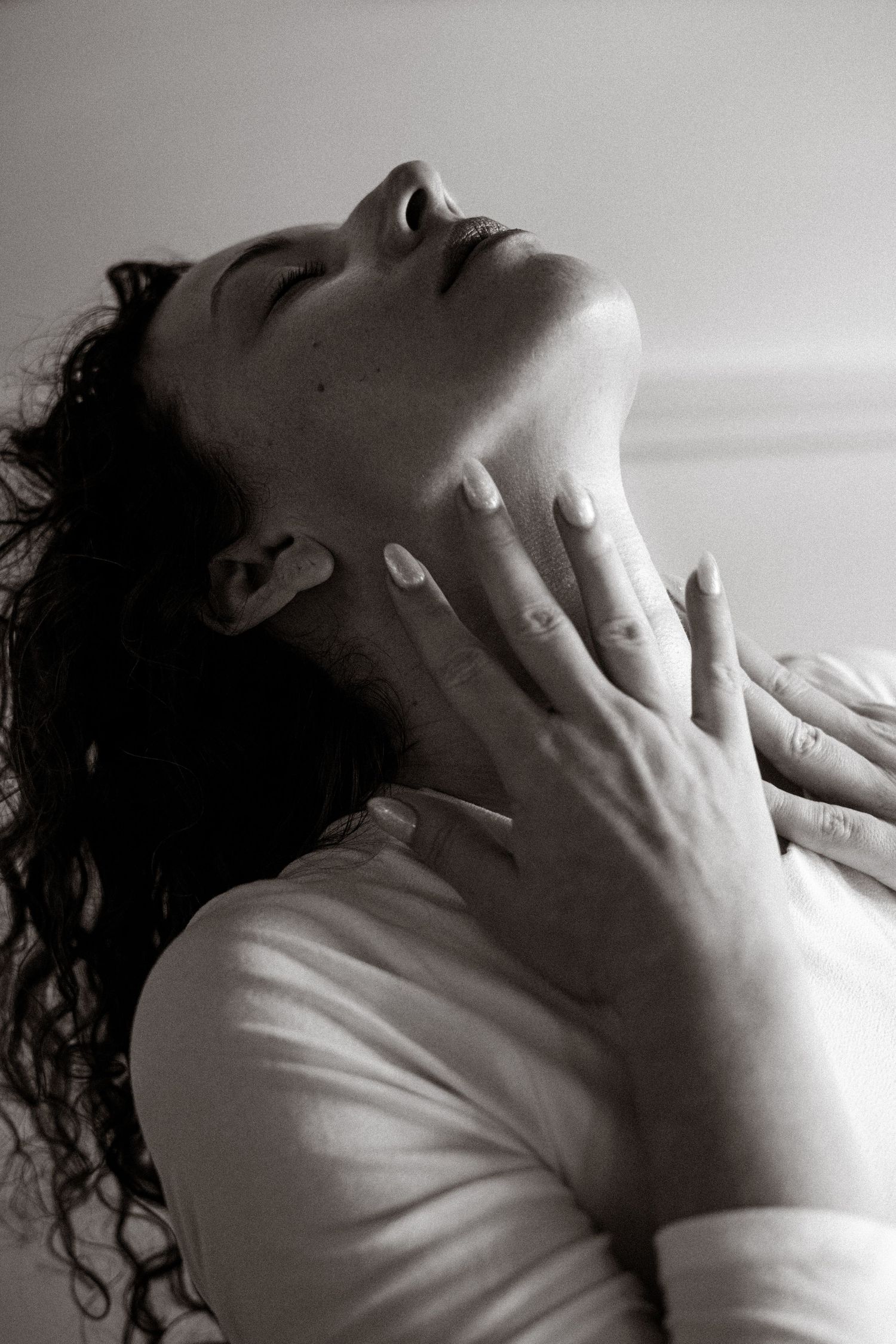 Dramatic black and white portrait capturing intimate emotion with hands on neck.