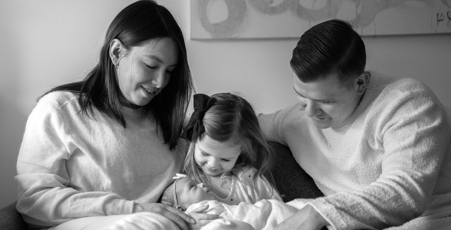 Black and white image of family sharing intimate moment while reading together.