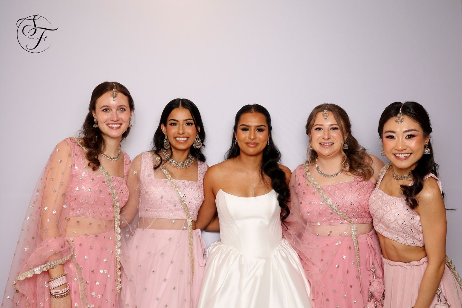 Bridesmaids wearing matching pink dresses pose together at a formal event.