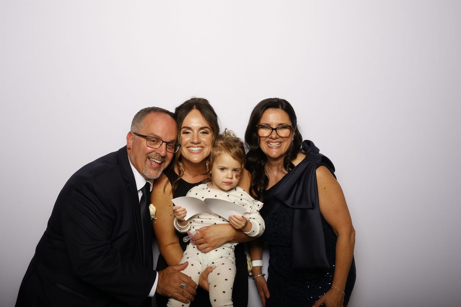 A family of four poses together against a gray backdrop in a studio portrait setting.