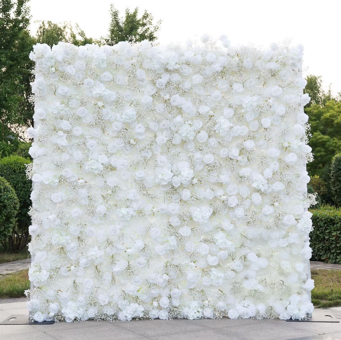 A white floral wall backdrop made of artificial flowers creates an elegant event decoration display.