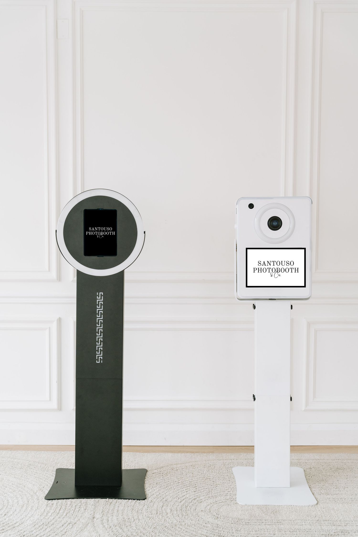 Four minimalist photo booth kiosks in white and green colors displayed against a white wall with decorative molding.