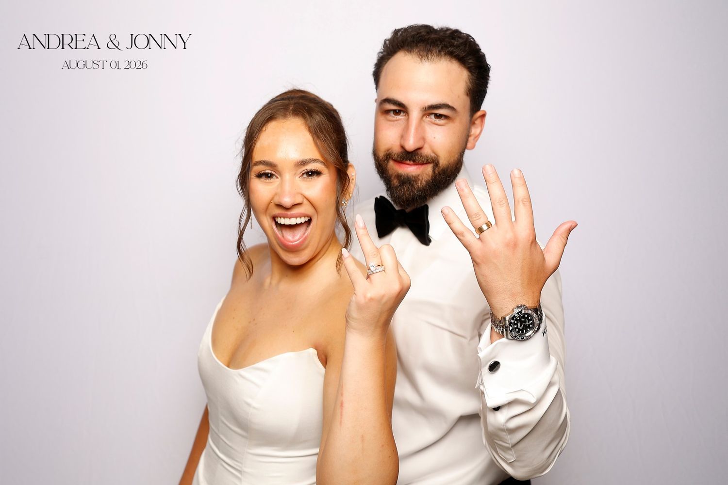Andrea and Jonny pose joyfully in a wedding photo booth, showing off their rings on August 14, 2021.