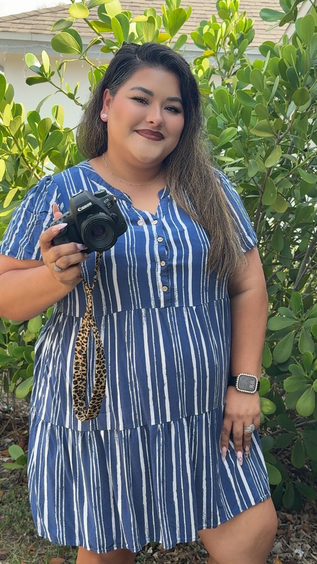 Julia Camacho, photographer and founder of Captured Moments Photography, posing with her camera as a family, sports, and event photographer