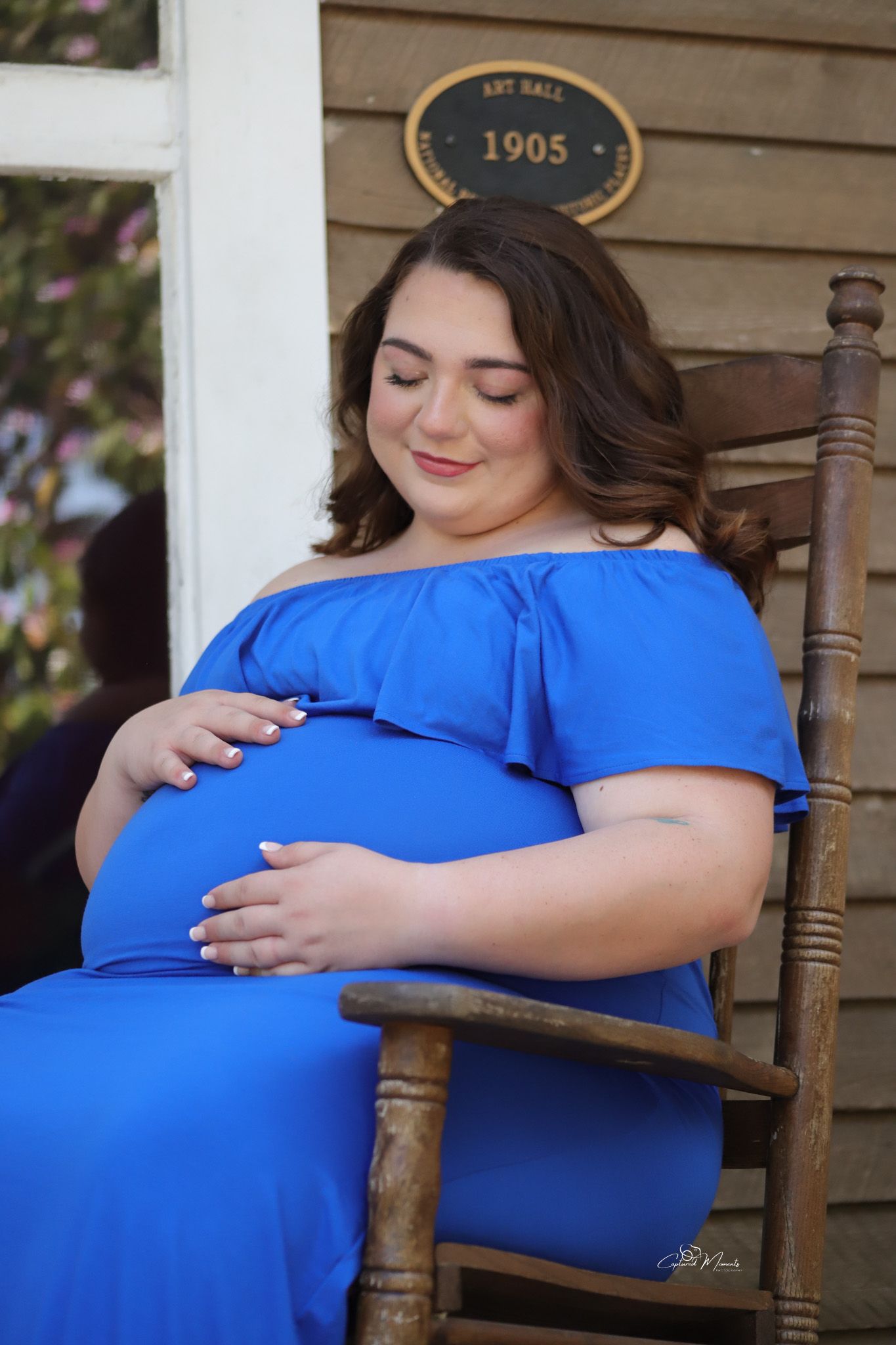 Beautiful maternity portrait of a mother-to-be sitting in a rocking chair during a pregnancy photo session captured by Captured Moments Phot