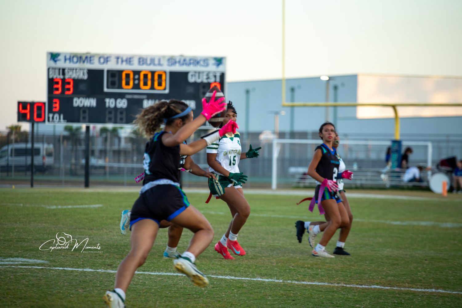 Girls flag football team celebrating together on the field at Bonita Springs High School during a game captured by Captured Moments Photogra