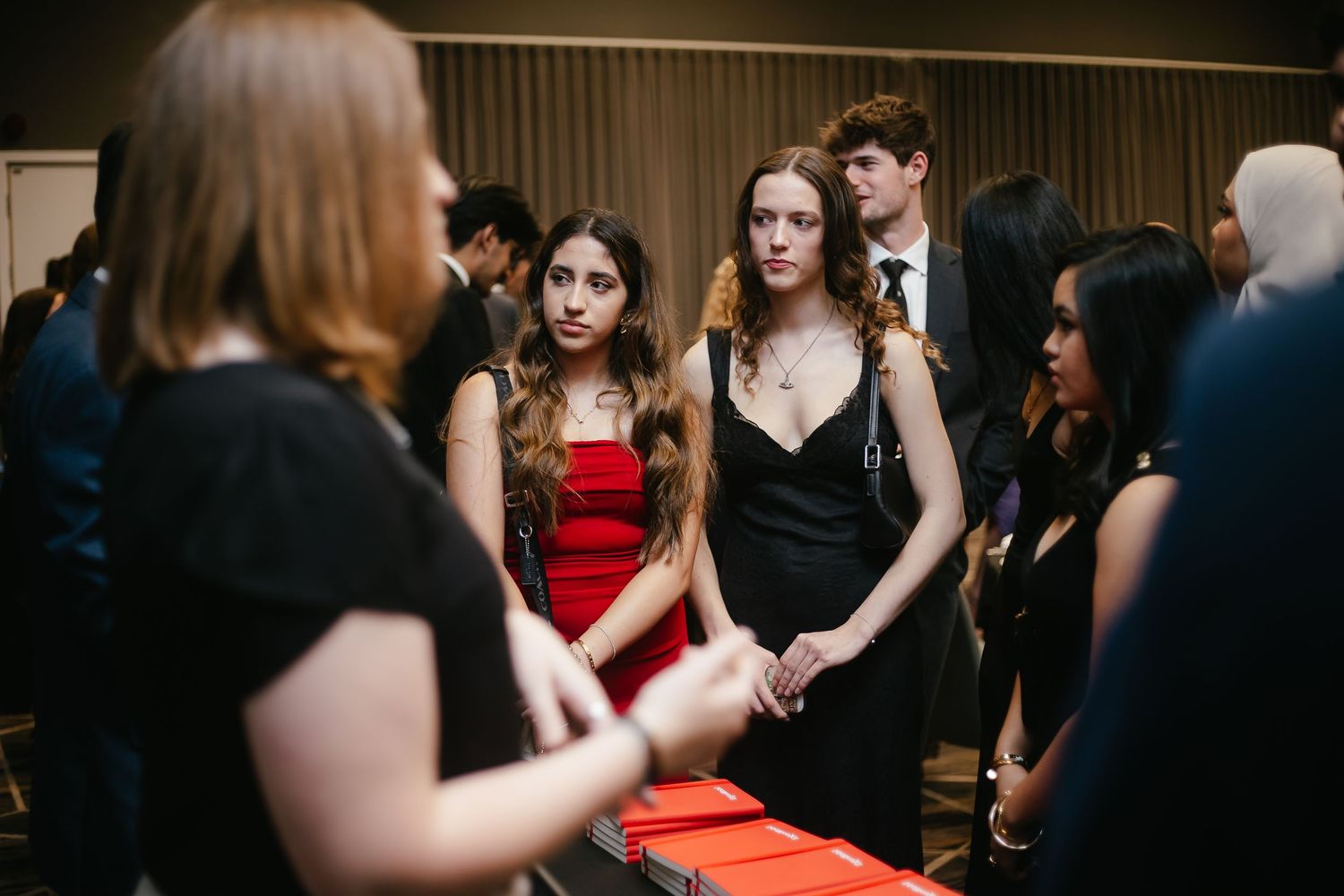 Formal event with guests mingling in front of a dark backdrop.