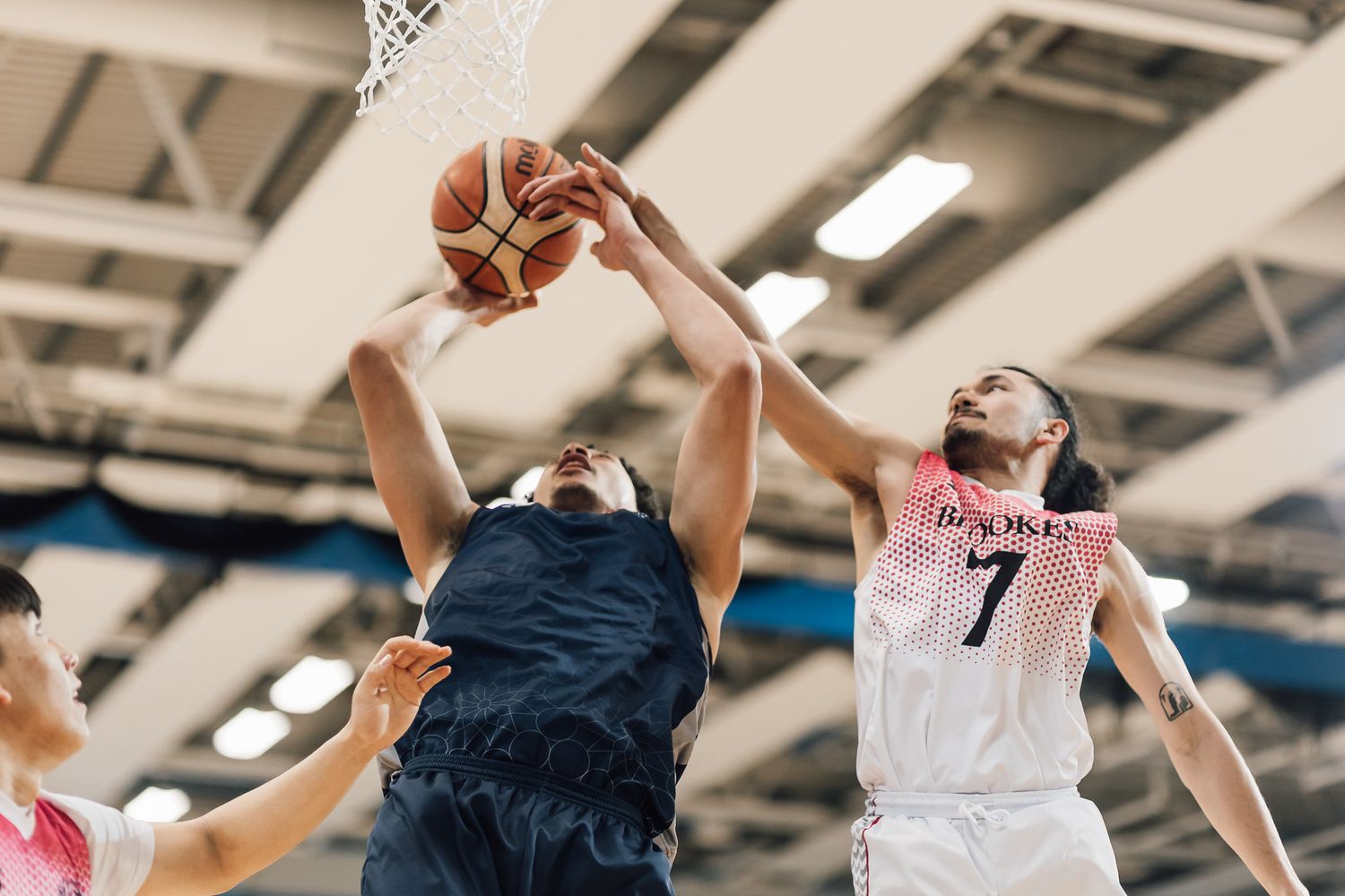 Basketball players jumping high to compete for the ball during an indoor match.