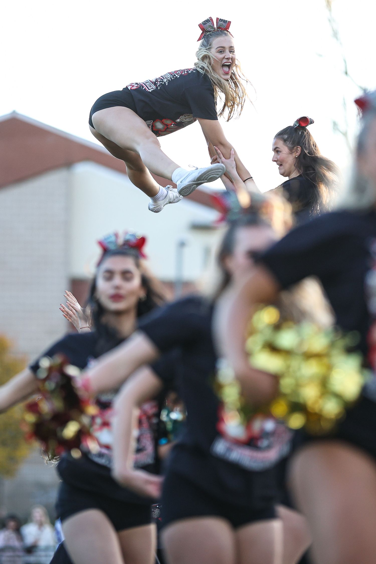 Dance team performs aerial moves and jumps during an energetic outdoor routine.