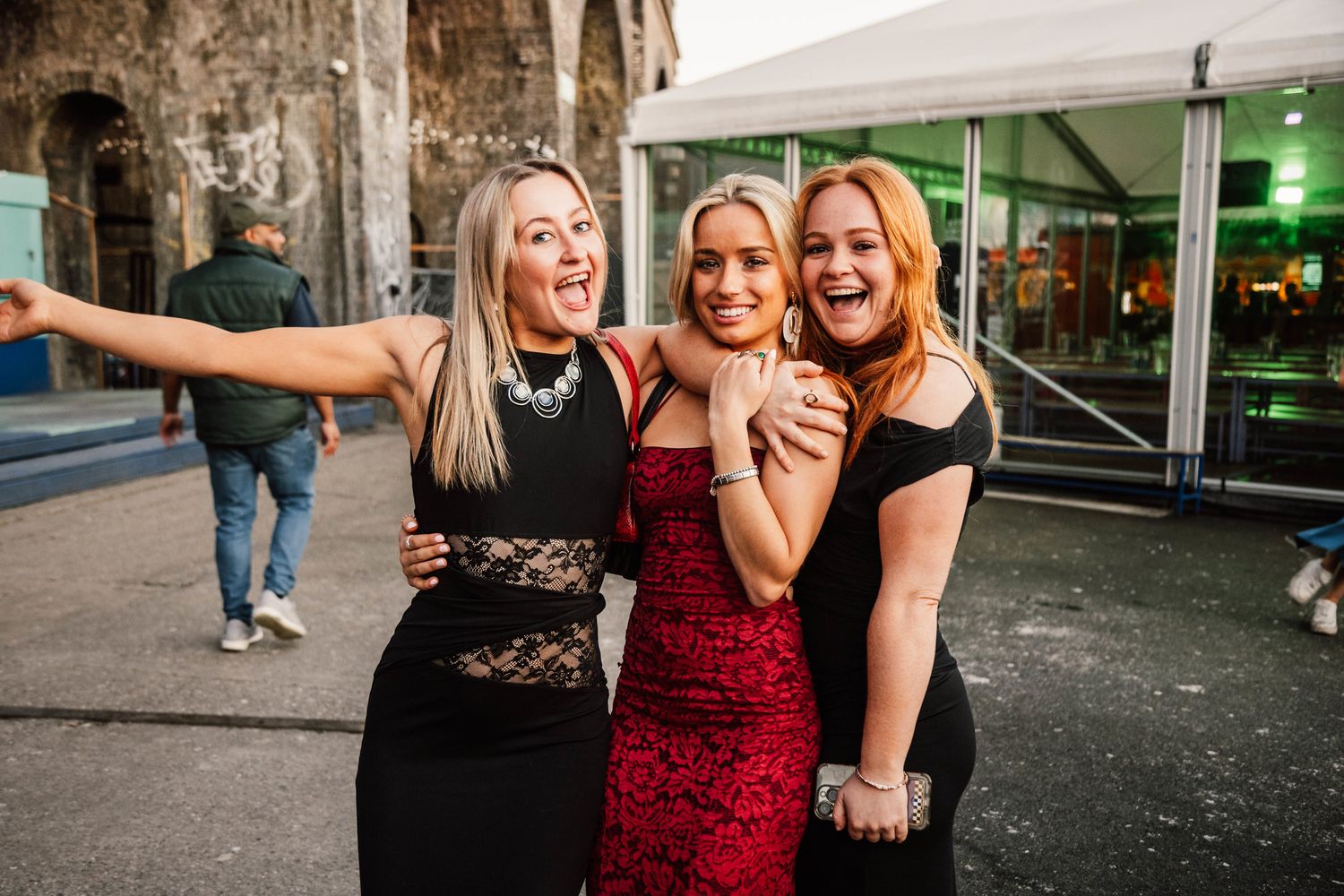 Party-goers having fun outside at night near brick buildings and storefronts.