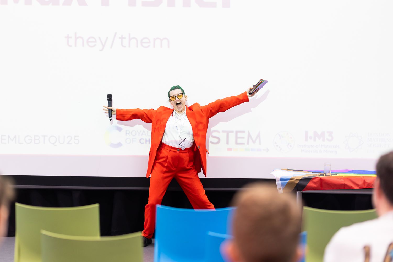 Presenter in bright red attire speaking enthusiastically during a conference session.