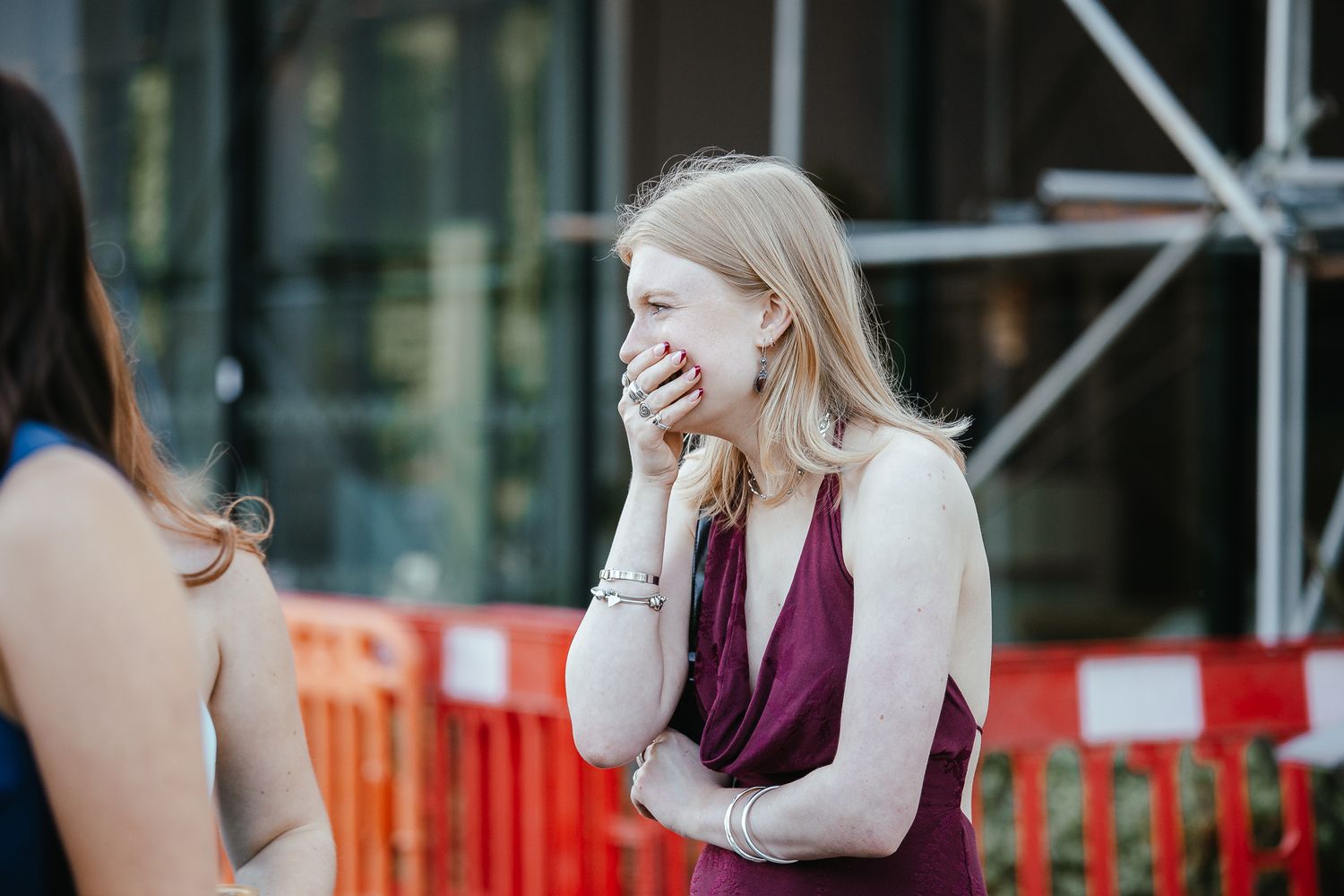 Wedding guests in formal attire laughing together during outdoor cocktail hour.