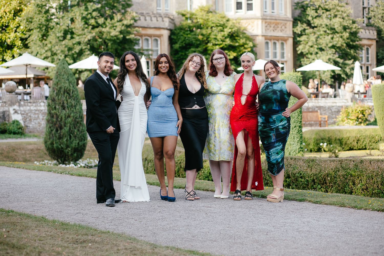 Group photo of wedding guests on a landscaped garden path.