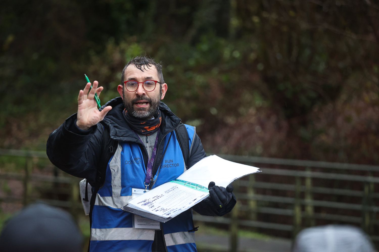 An official holding a clipboard and making signals during an outdoor sporting event.