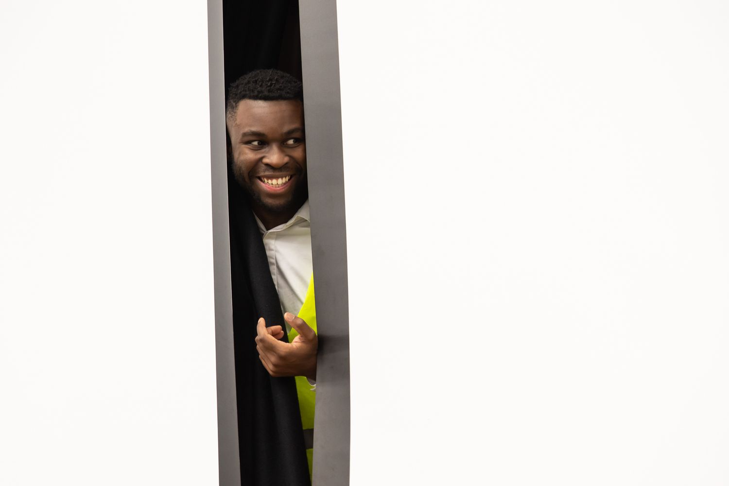 Performers peeking out playfully from behind a white wall or curtain.