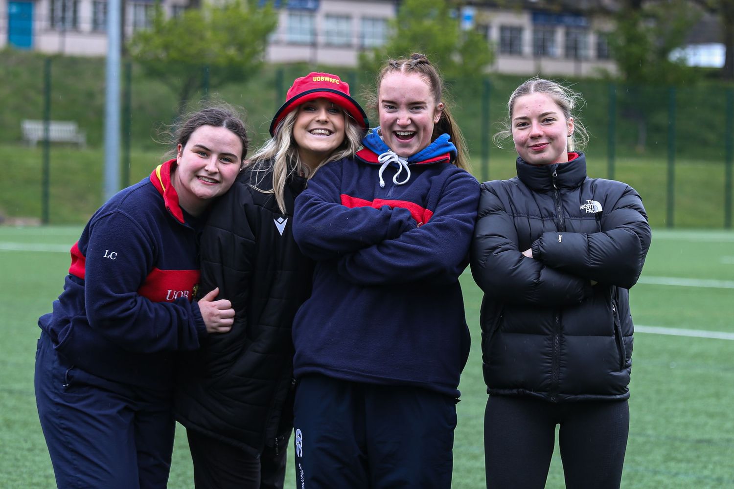 A group of coaches standing together on a sports field wearing athletic apparel.