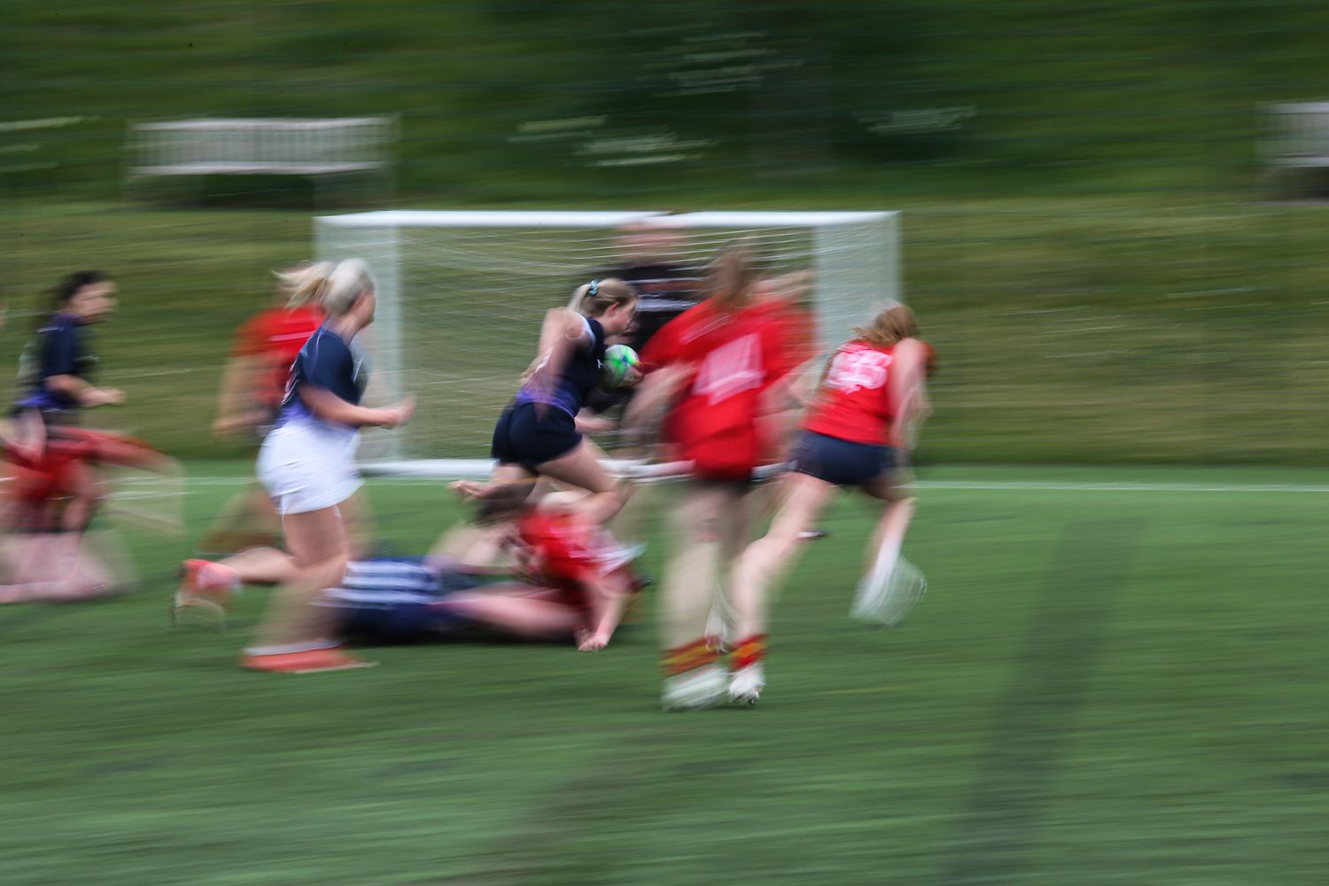 Athletes training on a grass field shown in motion blur.