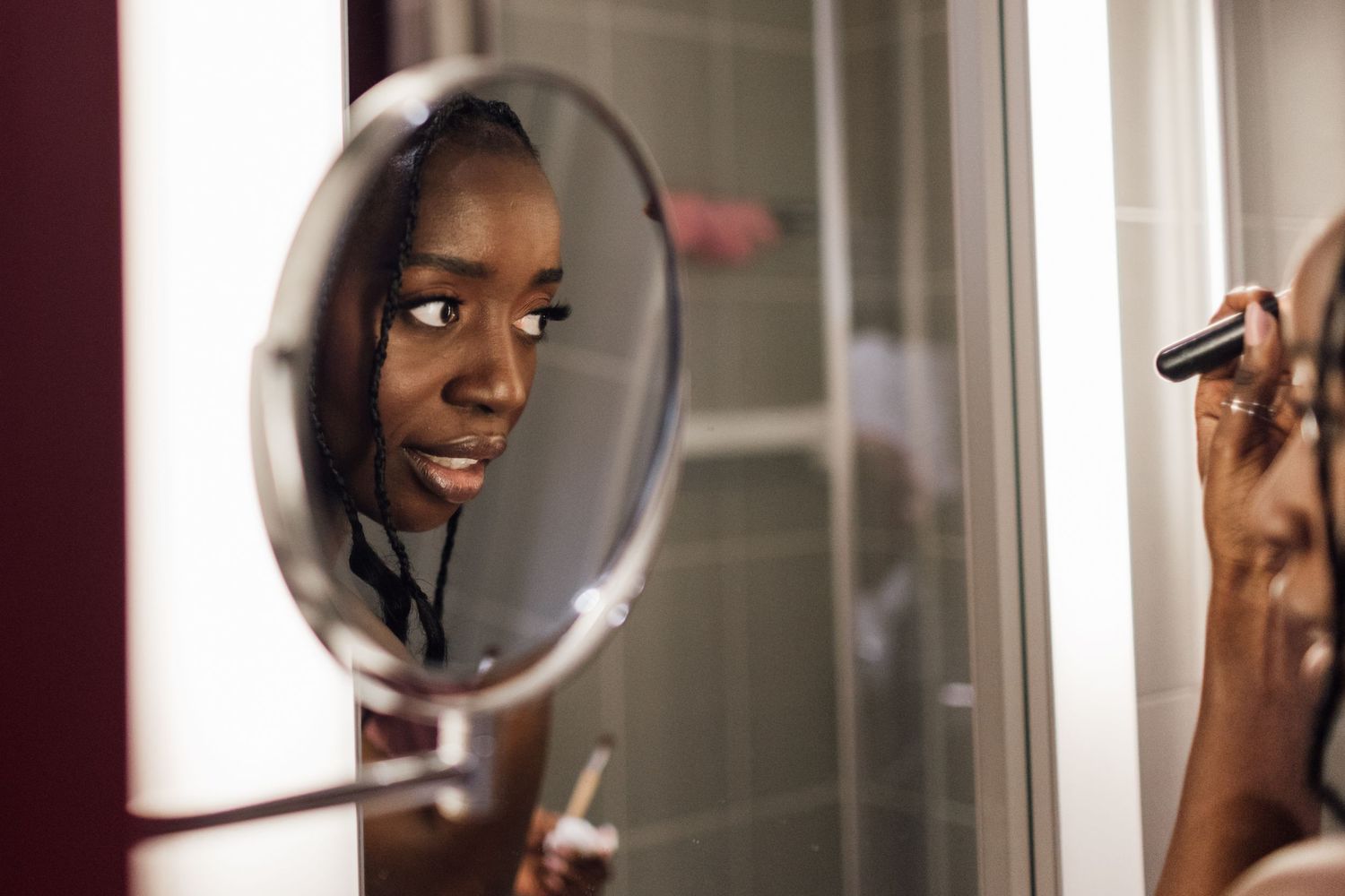 Wedding makeup application reflected in vanity mirror.