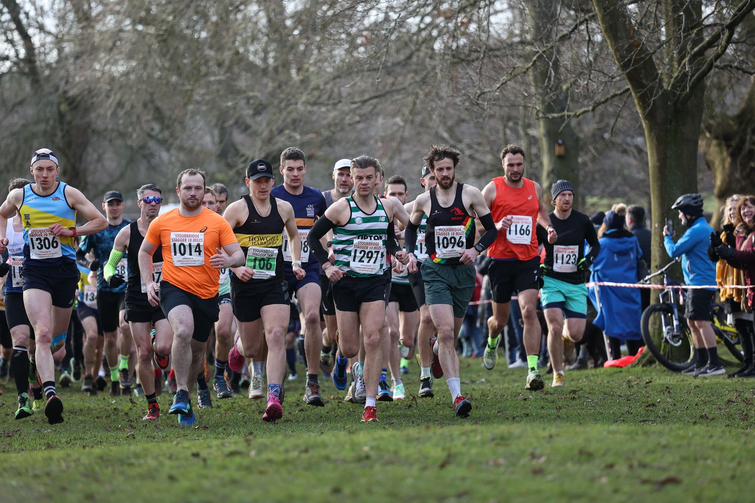 Large group of runners gathered at the start line of a cross country race through wooded parkland.