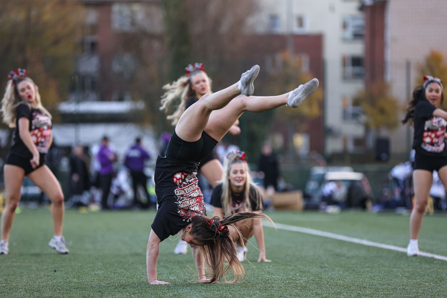 Performers execute acrobatic moves and formations during an outdoor dance routine.