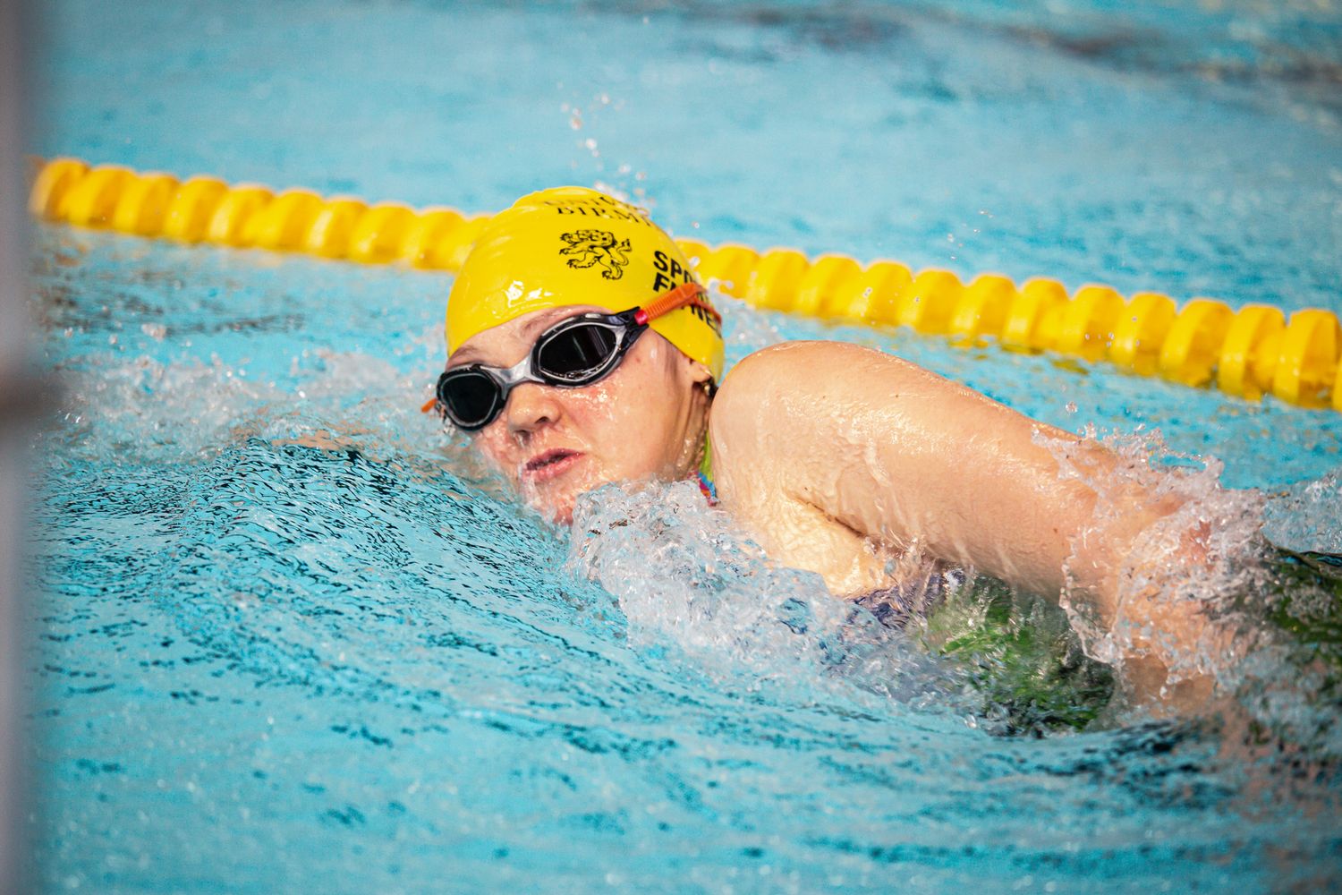 Competitive swimmer doing butterfly stroke in a pool with yellow lane dividers.