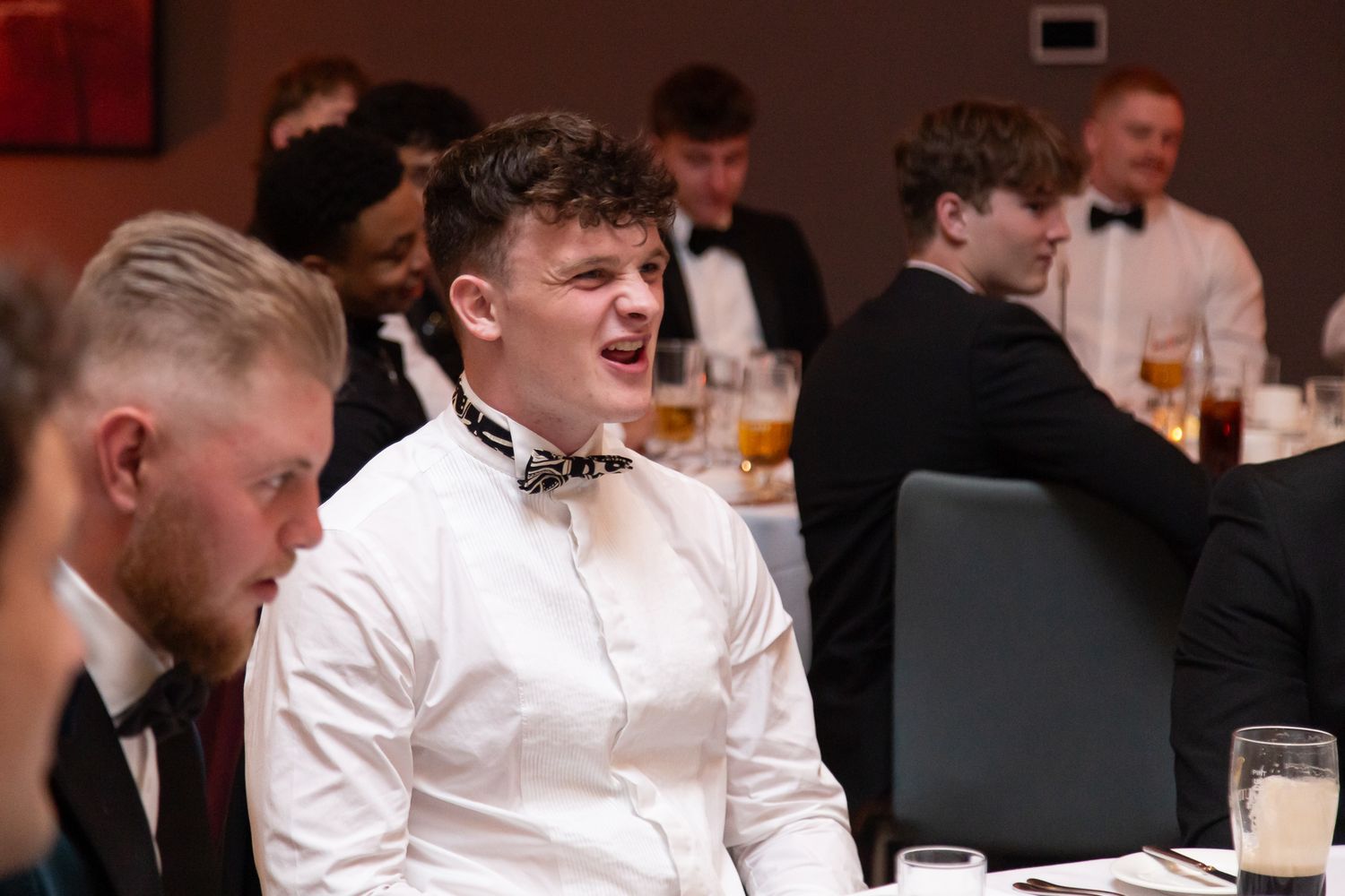 Celebratory gathering with guests in formal attire at an indoor banquet.