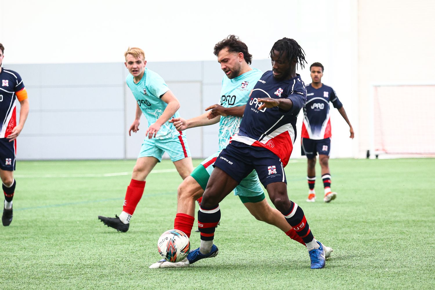 Soccer players competing for ball possession during indoor practice match.