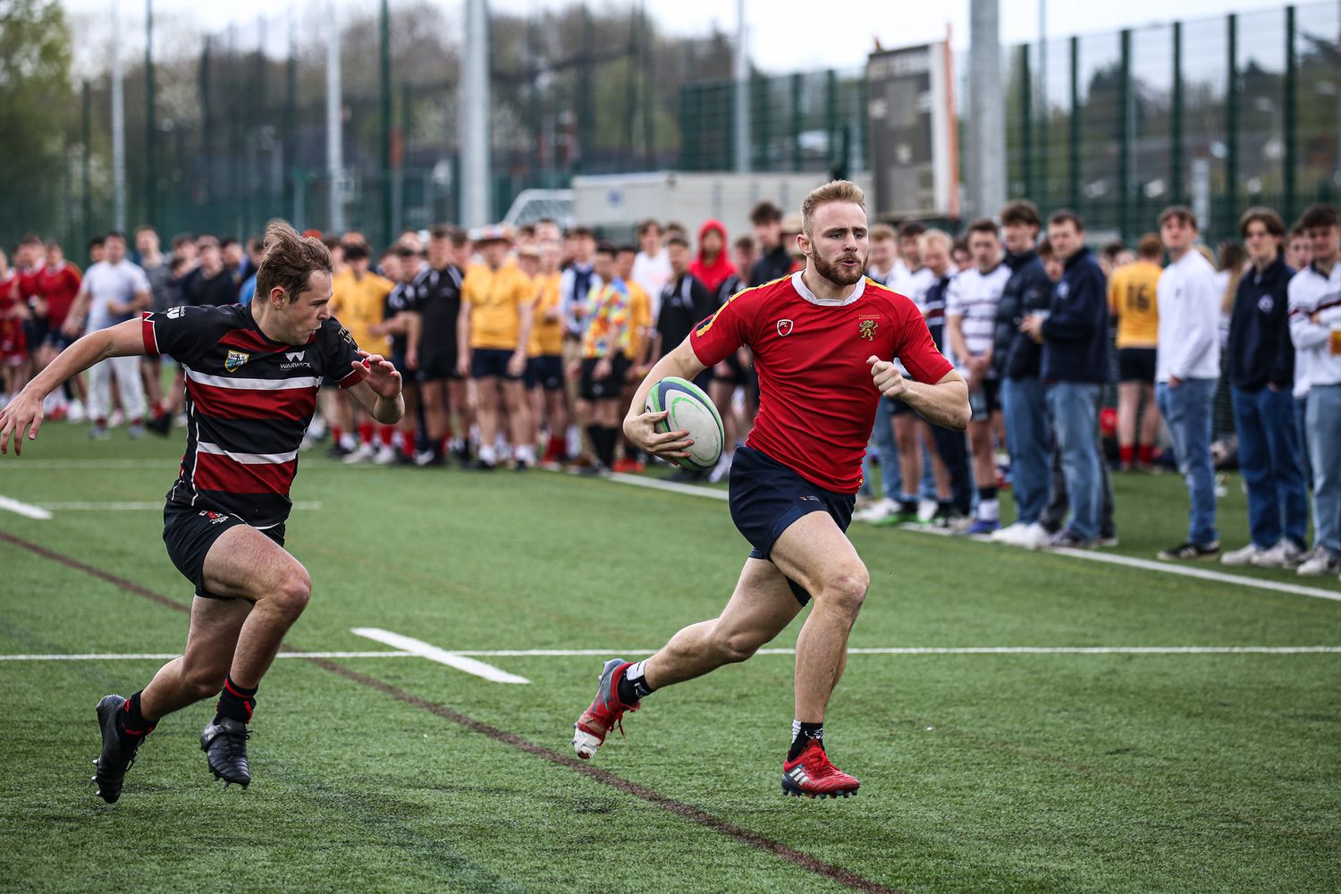 Athletes compete in a rugby match on an outdoor sports field.