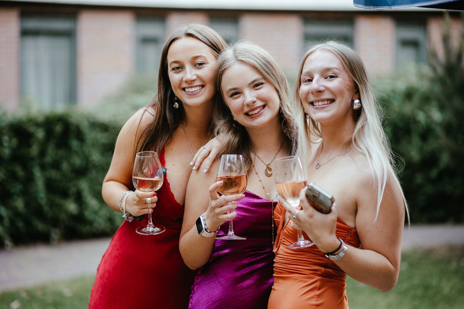 Bridesmaids in colorful dresses toasting with champagne glasses outdoors.
