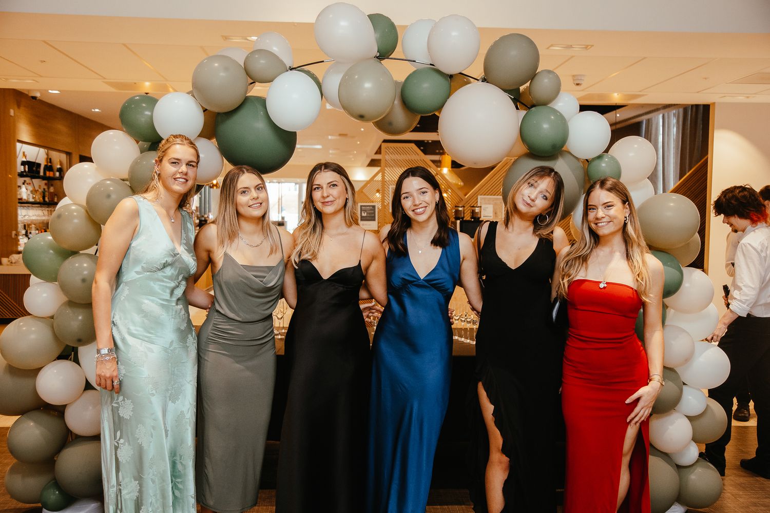 Formal event setup with elegant balloon arch and guests in evening gowns.