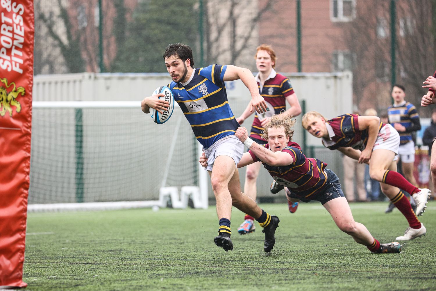 Rugby players tackle and dive during an intense play on the field.