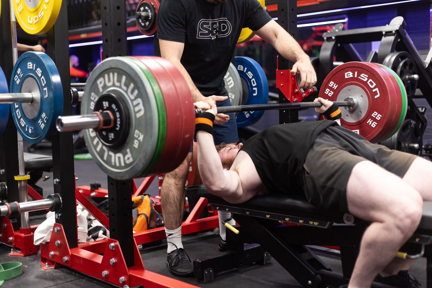 Close-up of weightlifting equipment and hands gripping barbells during strength training.