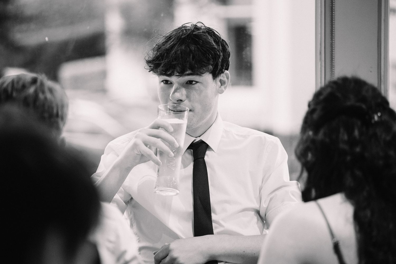 Black and white photo of guests in formal attire mingling at an event.