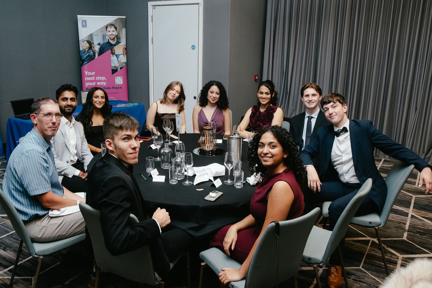 Wide shot of diverse group seated at tables in modern conference or event space.