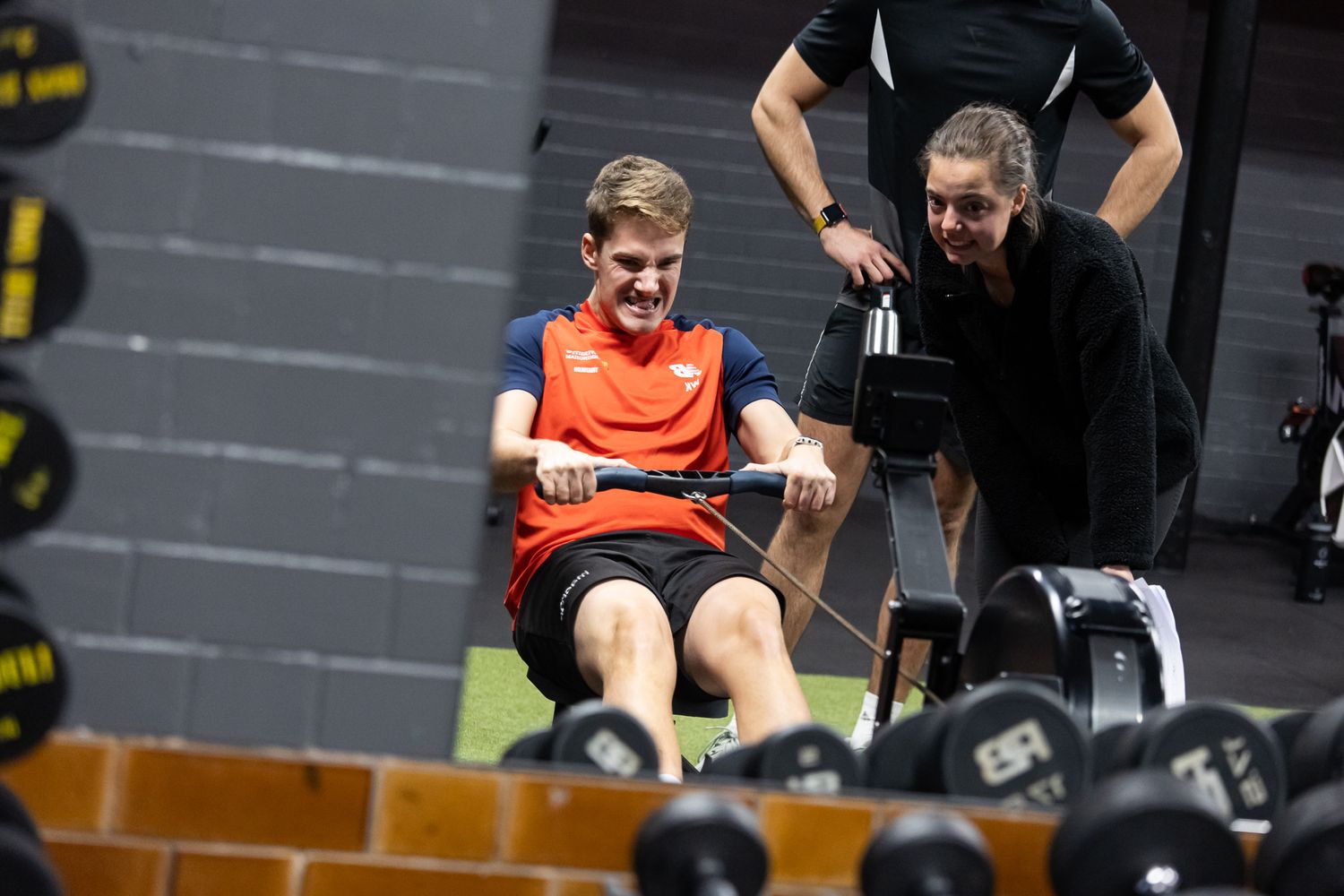 Athletes exercising with weight equipment in a modern gym facility.