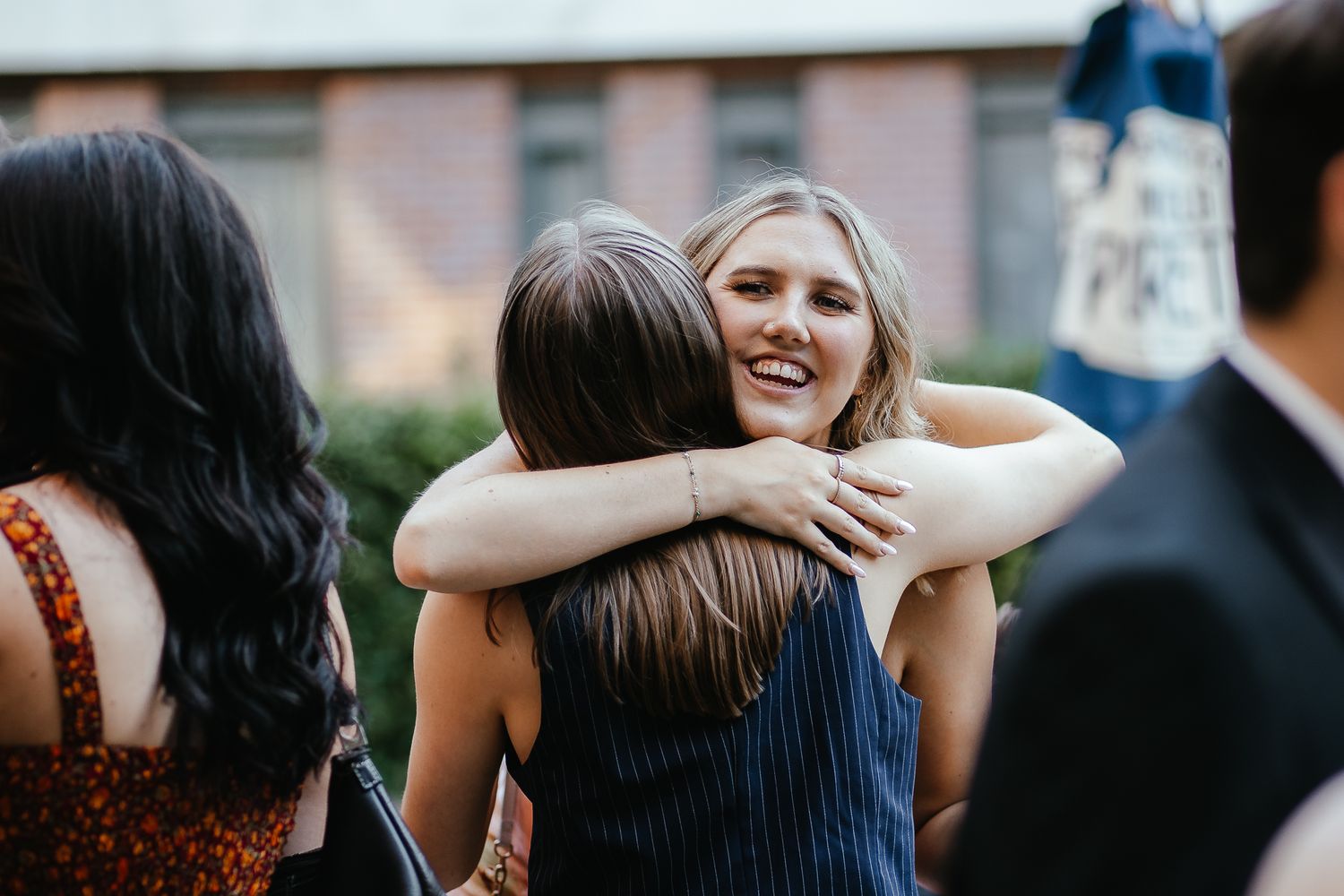 Friends sharing hugs and laughter at an elegant evening celebration.