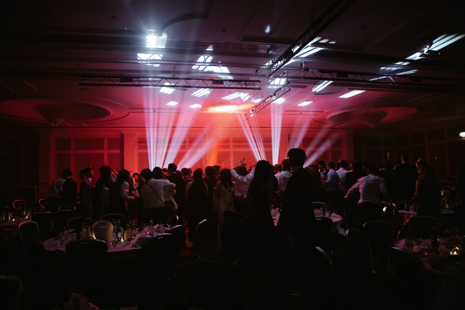 Dark event space with dramatic lighting and silhouettes of people celebrating.