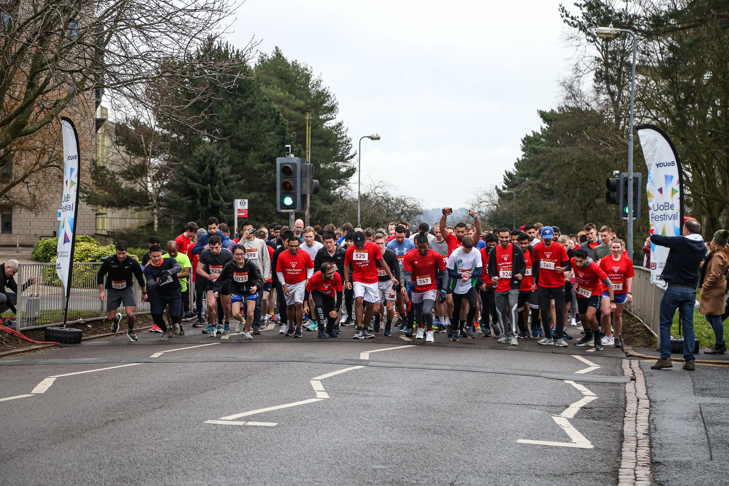 Large group of runners in red and blue shirts gather on a street for a community running event.