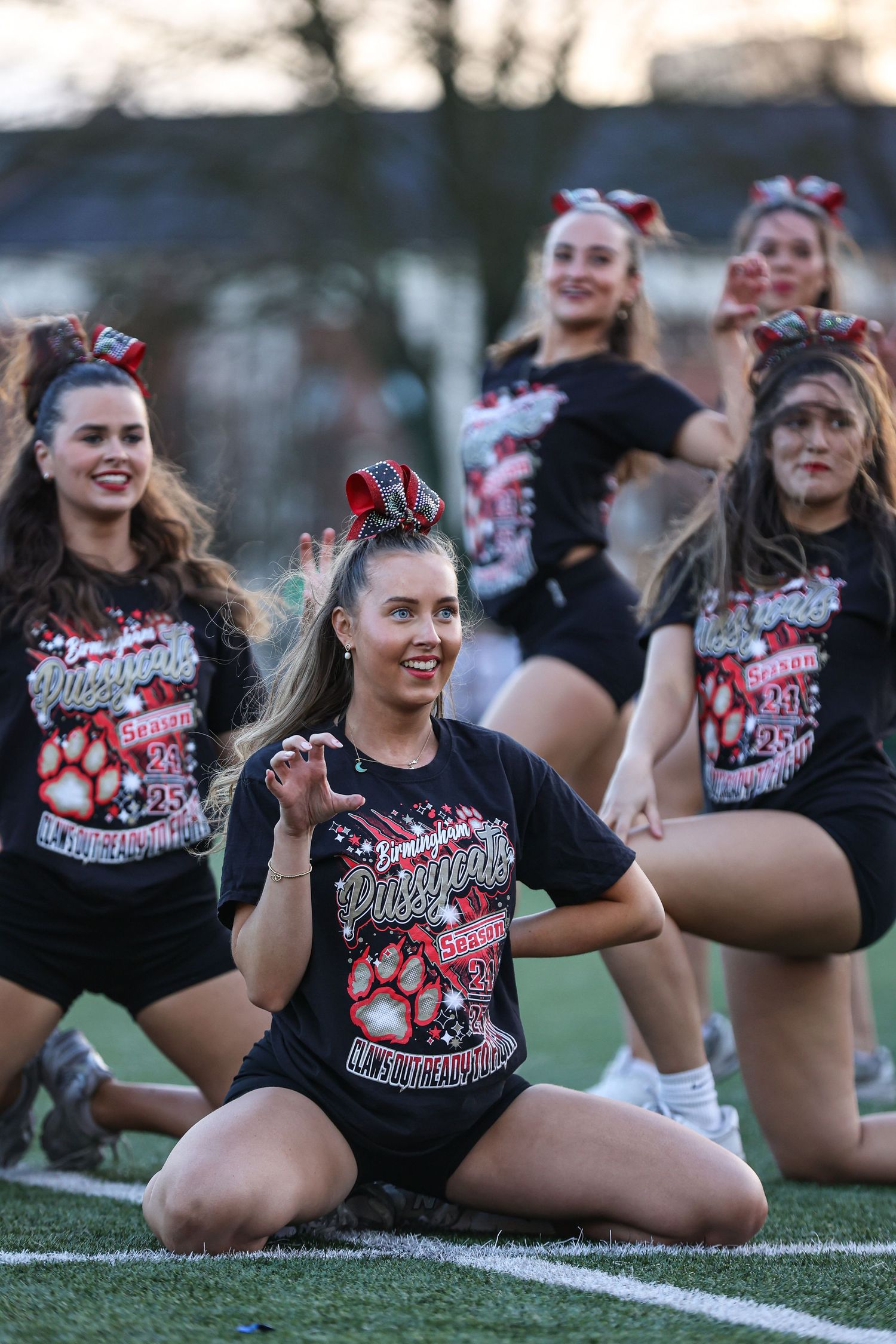 Dance team members strike seated poses during a choreographed field performance.