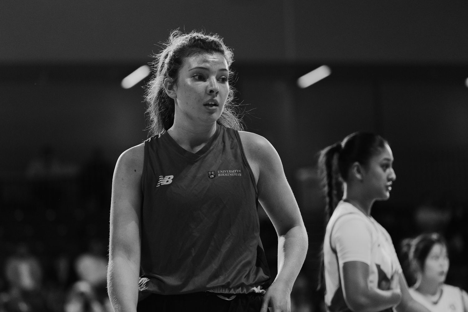 Black and white action shot of basketball players in motion during game.